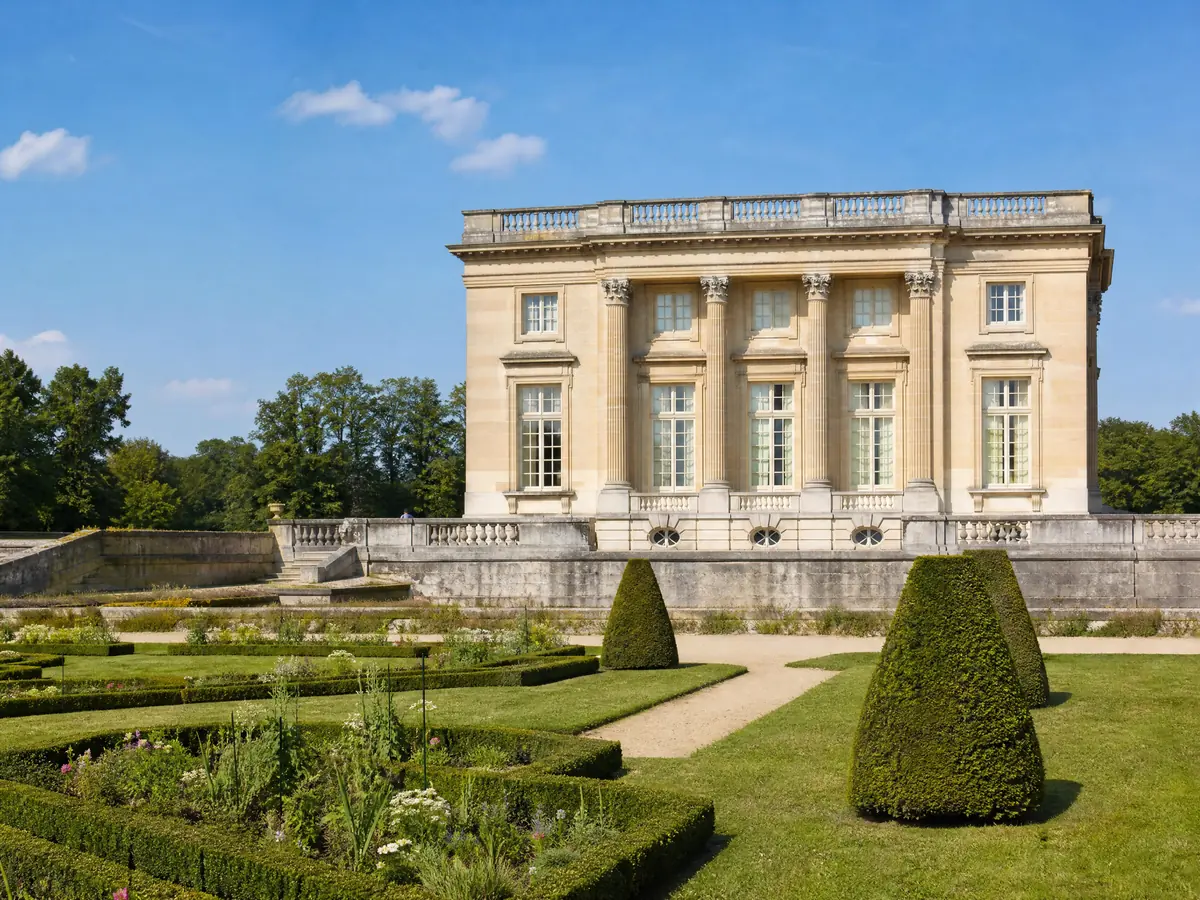 Die helle Steinfassade des Petit Trianon hinter einem Rasen